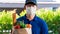 Asian deliver man in uniform with respirator face mask is delivering the paper bag waiting for the customer in front of the home