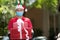 Asian delivery man wearing face mask and gloves in red uniform and Christmas hat delivering present and gift boxes during COVID-19