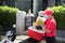 Asian delivery man wearing face mask and gloves in red uniform delivering  groceries bag of food, fruit, vegetable and drink to re