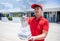 Asian delivery servicemen wearing a red uniform with a red cap and handling food boxes in plastic bags to give to the customer in