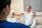 Asian Disabled senior elderly man sitting on sofa doing physiotherapist with support from therapist nurse. Older handicapped man u