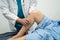 Asian doctor physiotherapist examining, massaging and treatment knee and leg of senior patient in orthopedist medical clinic nurse