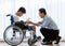 Asian doctor talking, support, and encouragement to a young disabled boy in a wheelchair