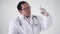 Asian doctor in a white coat with a stethoscope on a white background holds a syringe with medicine in his hand. He