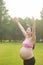 Asian Eastern Chinese happy beautiful pregnant woman hug embrace nature in green forest outdoor full of hope enjoy positive life