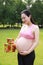 Asian Eastern Chinese happy pregnant woman in yoga dress hands hold her belly expecting baby to born gift box beside