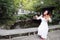 Asian Eastern Chinese young artist player woman carry play violin perform music park garden nature sit on bench outdoor nature