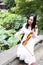 Asian Eastern Chinese young artist player woman carry play violin perform music park garden nature sit on bench outdoor nature