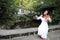 Asian Eastern Chinese young artist player woman carry play violin perform music park garden nature sit on bench outdoor nature