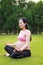 Asian Eastern Chinese young pretty pregnant girl woman do yoga sit in meditation, do lotus gesture of yoga with closed-eyes nature