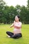 Asian Eastern Chinese young pretty pregnant girl woman do yoga sit in meditation, do lotus gesture of yoga over sunset,namaste