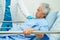 Asian elder senior woman patient holding bed rail while lie down with hope waiting her family in hospital