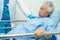 Asian elder senior woman patient holding bed rail while lie down with hope waiting her family in hospital