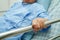 Asian elder senior woman patient holding bed rail while lie down with hope waiting her family in hospital