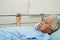 Asian elder senior woman patient holding bed rail while lie down with hope waiting her family in hospital