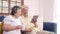 Asian elderly couple using tablet and drinking coffee in living room at home.