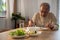 Asian Elderly retired grandfather stay at home with painful face sitting alone on eating table in house. Depressed mature Senior o