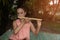 Asian elderly woman blowing native bamboo flute for relaxation in the garden.