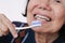 Asian elderly woman trying use toothbrush .