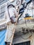 Asian electrician on a ladder repairing wire of the power line on electric power pole