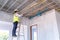 Asian electrician wearing a mask installing laying electrical cables on the ceiling with pliers inside the house under