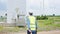 Asian engineer on maintenance job at wind farm power station, wind turbine in background