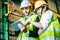 Asian engineer man wearing white helmet with his assistant and using laptop to monitoring the production status.