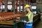 Asian engineer worker inspecting inside the steel manufacturing factory while looking at the laptop for monitoring the improvement