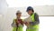 Asian engineer or Young Female Architect put on a helmet for safety and talk with a contractor on a construction building factory