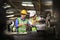 Asian engineering manager and mechanic worker in safety hard hat and reflective cloth using lathe machine in the factory