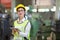 Asian engineering manager in safety hard hat and reflective cloth is inspecting inside the factory using digital tablet