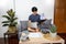Asian entrepreneur working at home on some project with his laptop at home with paperworks and documents on table in living room,