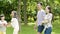 Asian family of 4 walking & laughing in park in sunny summer in slow motion