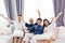 Asian family with adult children and senior parents raising hands up and sitting on a sofa at home. Happy and relaxing family time