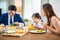 Asian family father, mother with children daughter eating breakfast food on dining table kitchen in mornings