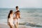 Asian family with fathers carrying his son on back and mother walking togerther along a beachfront beach while on vacation in the