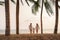 Asian family with fathers, mother and son are walking along a beachfront beach with coconut trees while on vacation in the summer