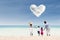 Asian family looking at heart cloud at beach