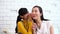 Asian family of teenage girl gossiping at mature woman\'s ears at home