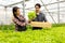 Asian farmer couple work in hydroponic vegetable greenhouse farm with happiness and joyful in row of plants background