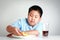 Asian fat boy eating pizza on a white table with soda water.