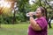 Asian fat woman drinking water bottle with workout outdoors exercising in park,