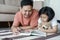 Asian father and daughter read books on the floor in the house, Self-learning concept