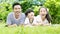 Asian father & his children lie on grassland reading story book