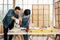 Asian father and son work as a woodworker or carpenter, Father teaches his son to drill holes in a wooden plank carefully together