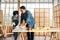 Asian father and son work as a woodworker or carpenter, Father teaches his son to saw a wooden plank with hack saw carefully