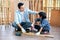 Asian father touch head of his son during drill the timber in home workplace of carpentering with happy emotion. Asian family