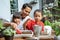 Asian father and two daughters are happy when using a shovel to grow potted plants