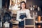 Asian female barista wear jean apron and holding blank blackboard menu at counter bar with smile face,cafe service