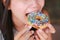 Asian female biting a rainbow donut